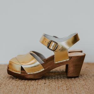 Gold metallic cross over sandal clog with ankle strap and a mid heel