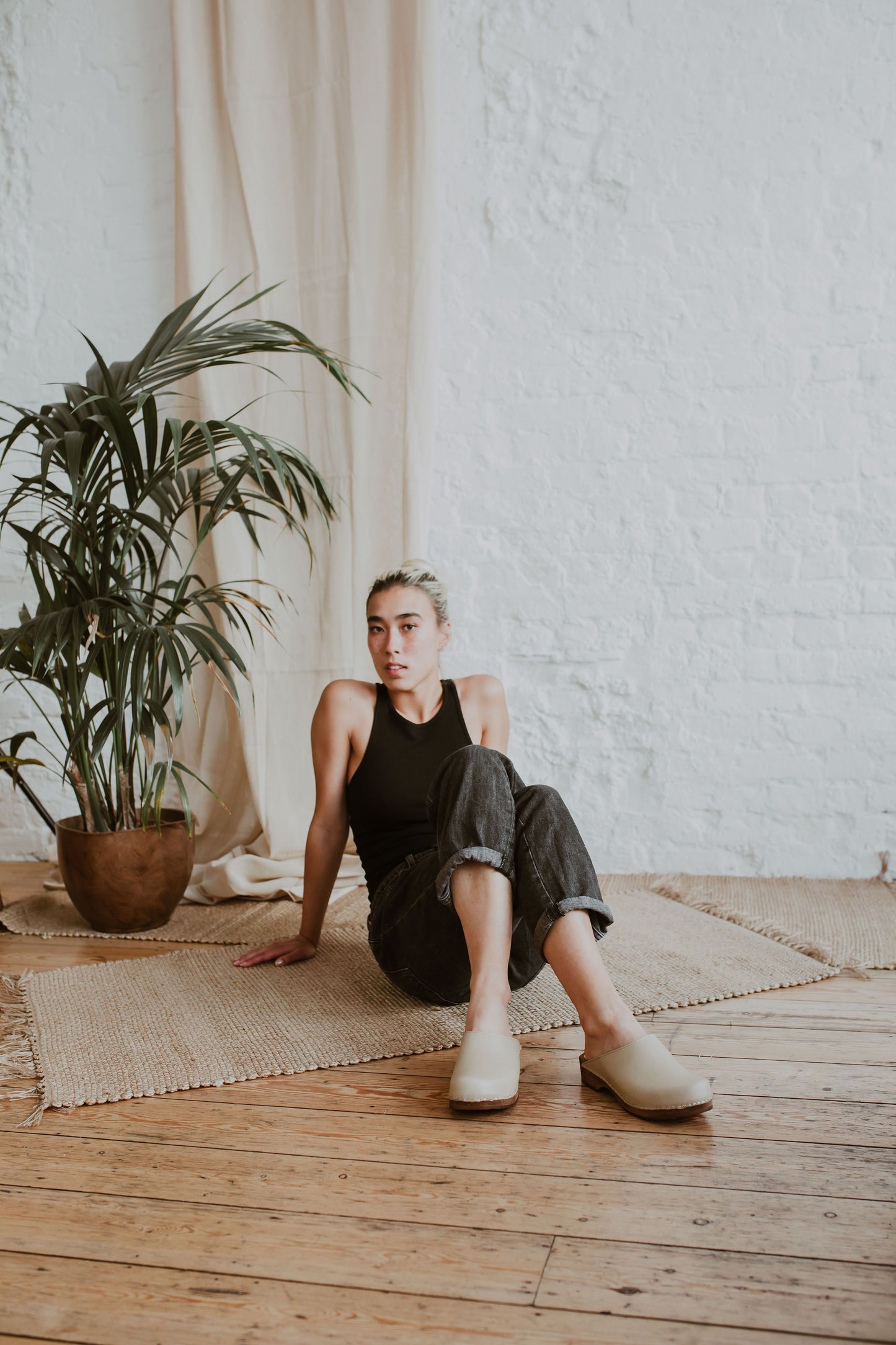 woman wearing black jeans and tank top with stone beige coloured low classic style swedish clog