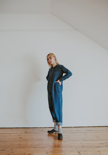 woman wears denim jumpsuit with thick socks and black low classic style swedish clog