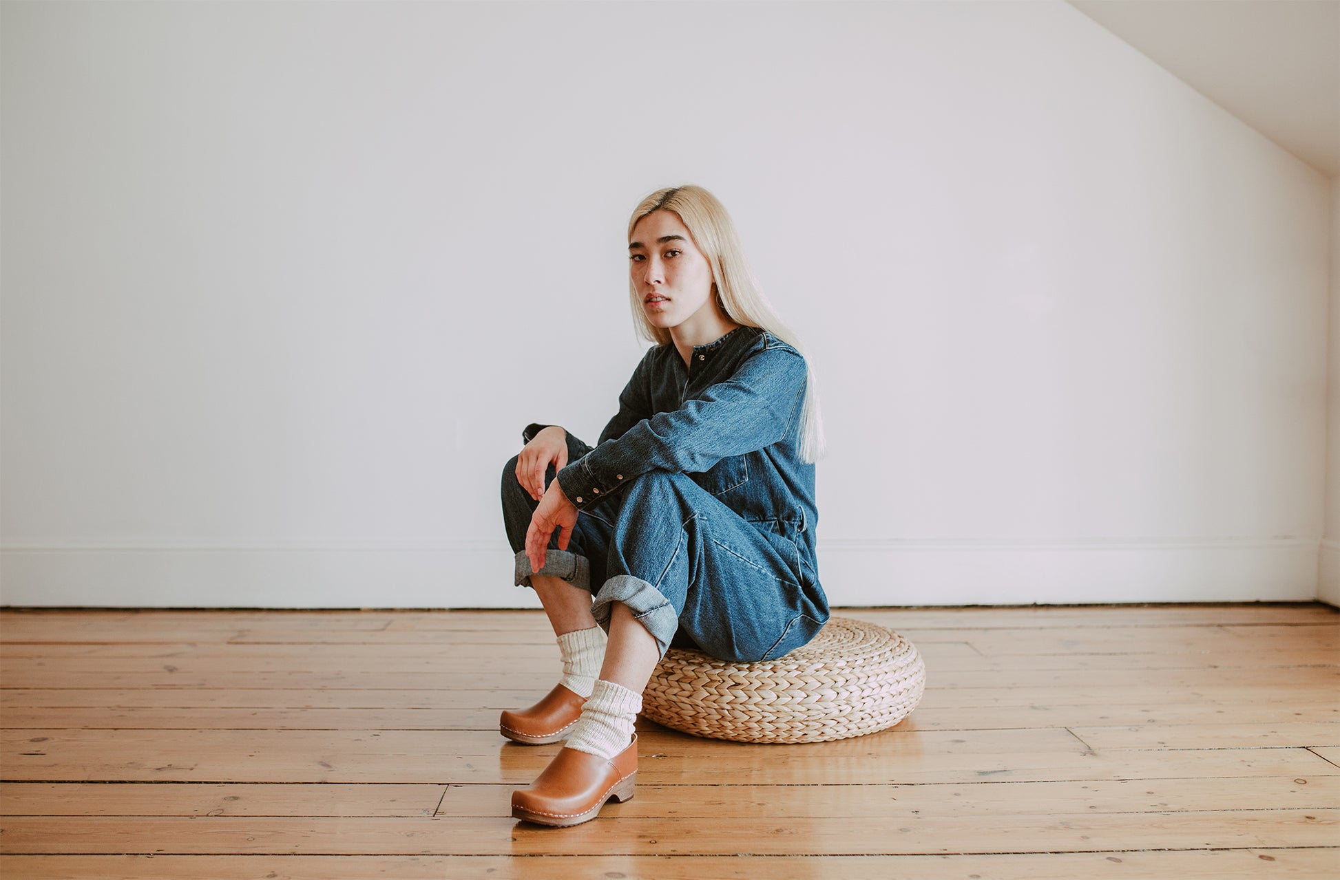 woman wears denim jumpsuit with cream socks and cumin tan low heel clog shoes