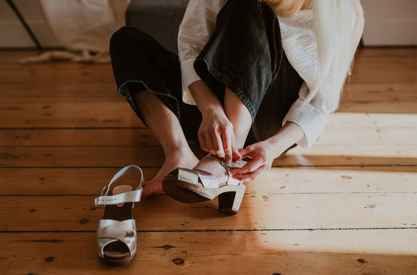 girl trying on silver cross over mid heel clog sandals