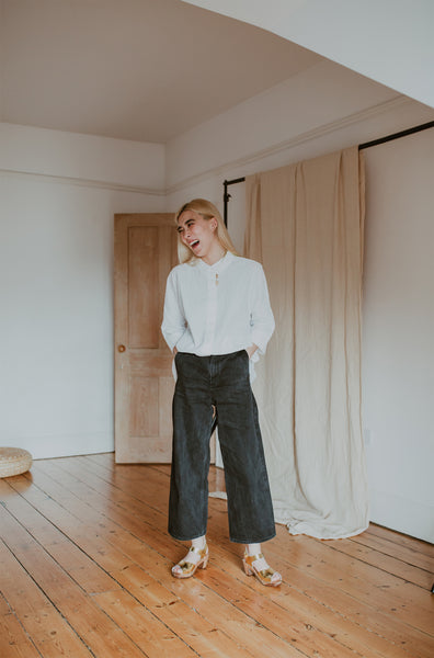 girl wears white shirt with black wide leg jeans and gold mid heel clog sandals