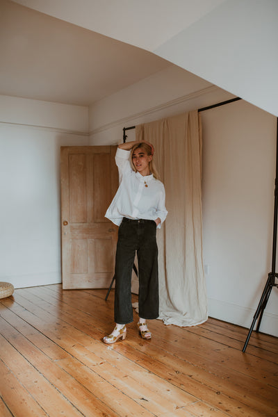 girl wears white shirt with black wide leg jeans and gold mid heel clog sandals