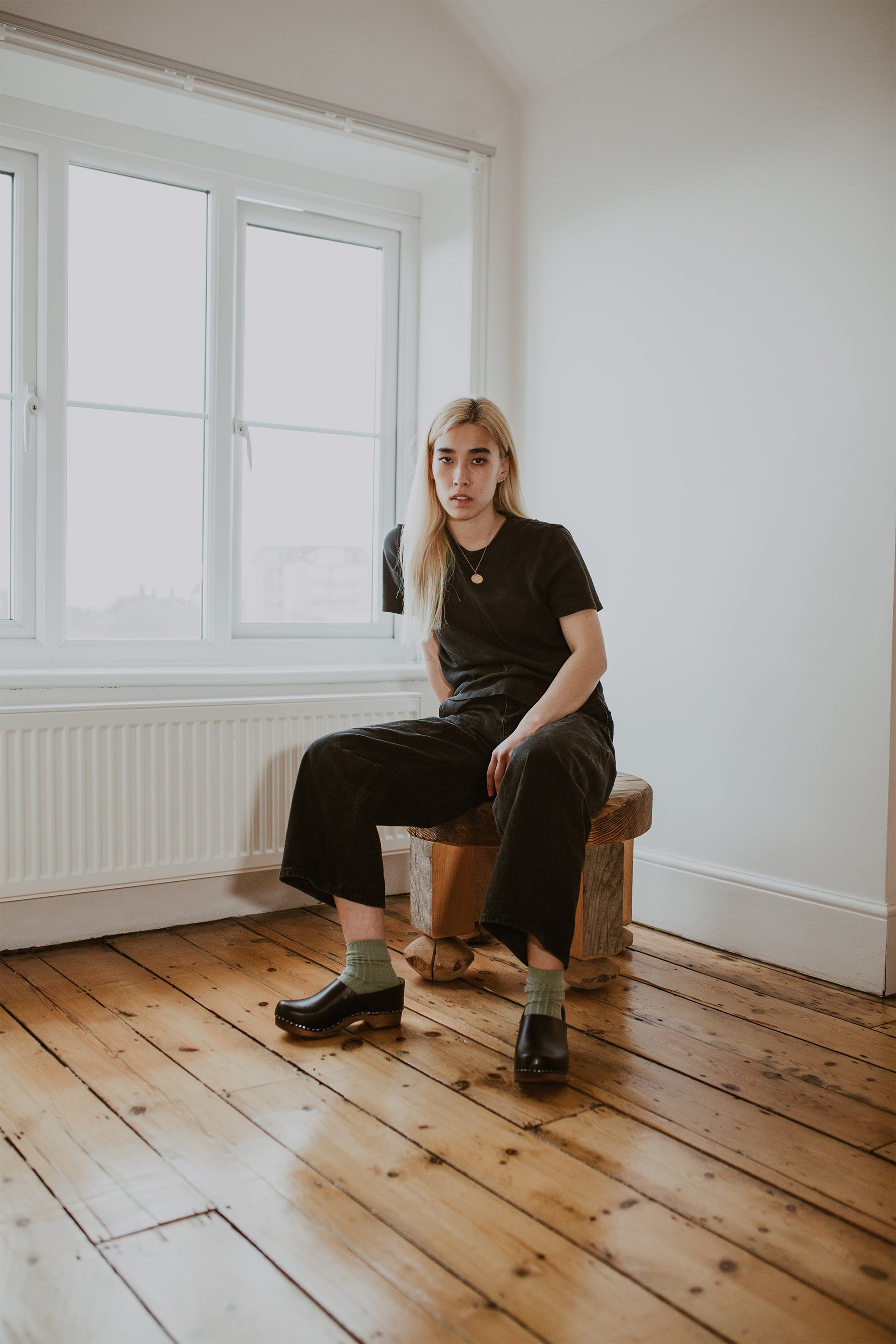 girl wears black jeans with sage green ribbed ankle socks and onyx low heel clog shoe