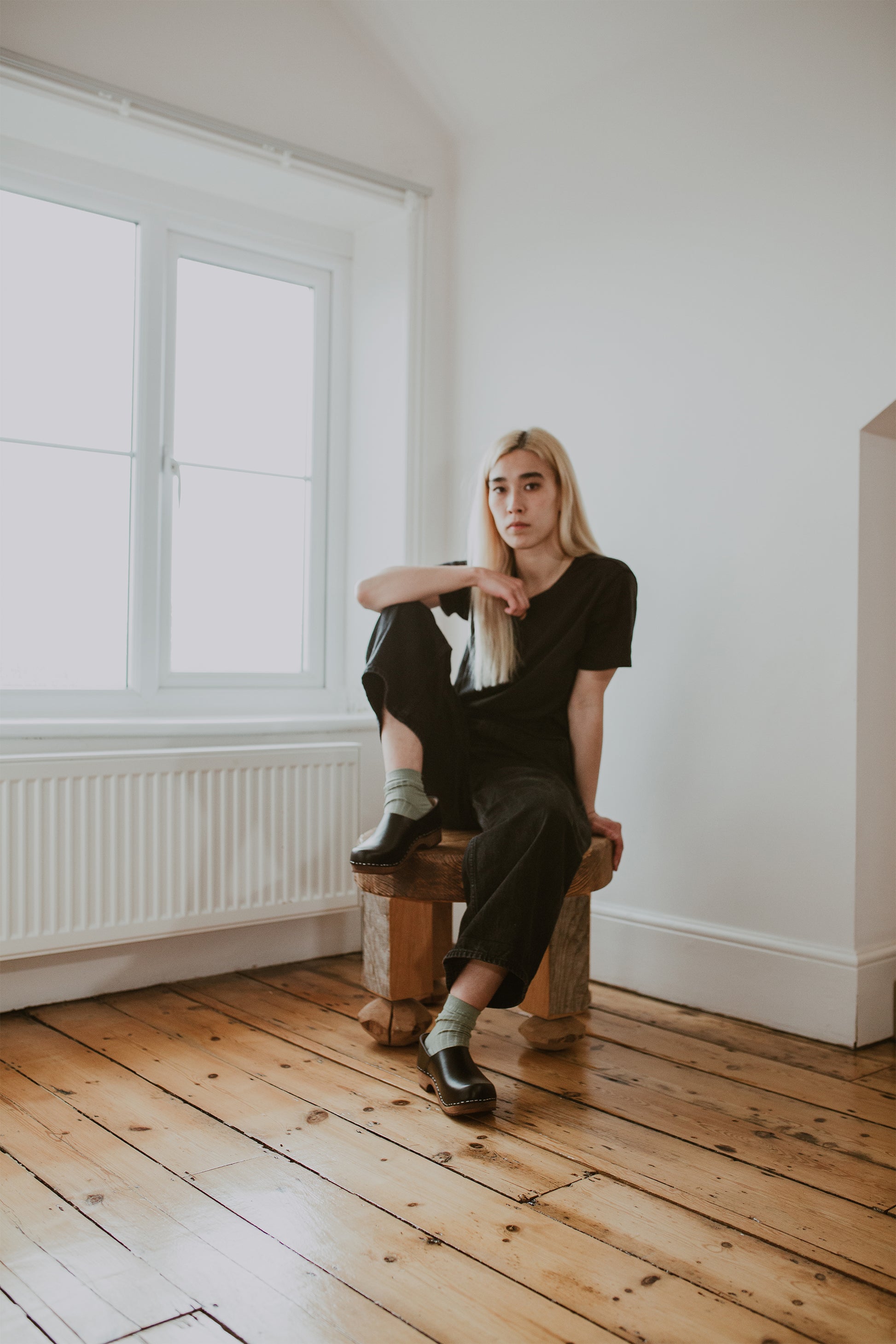 girl wears black jeans with sage green ribbed ankle socks and onyx low heel clog shoe