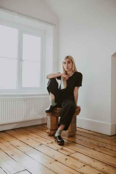 girl wears black jeans with sage green ribbed ankle socks and onyx low heel clog shoe