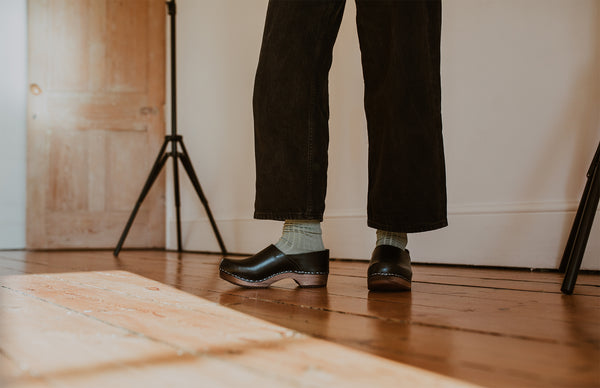 close up of woman's feet in sage green ribbed ankle socks and onyx low heel clog shoe