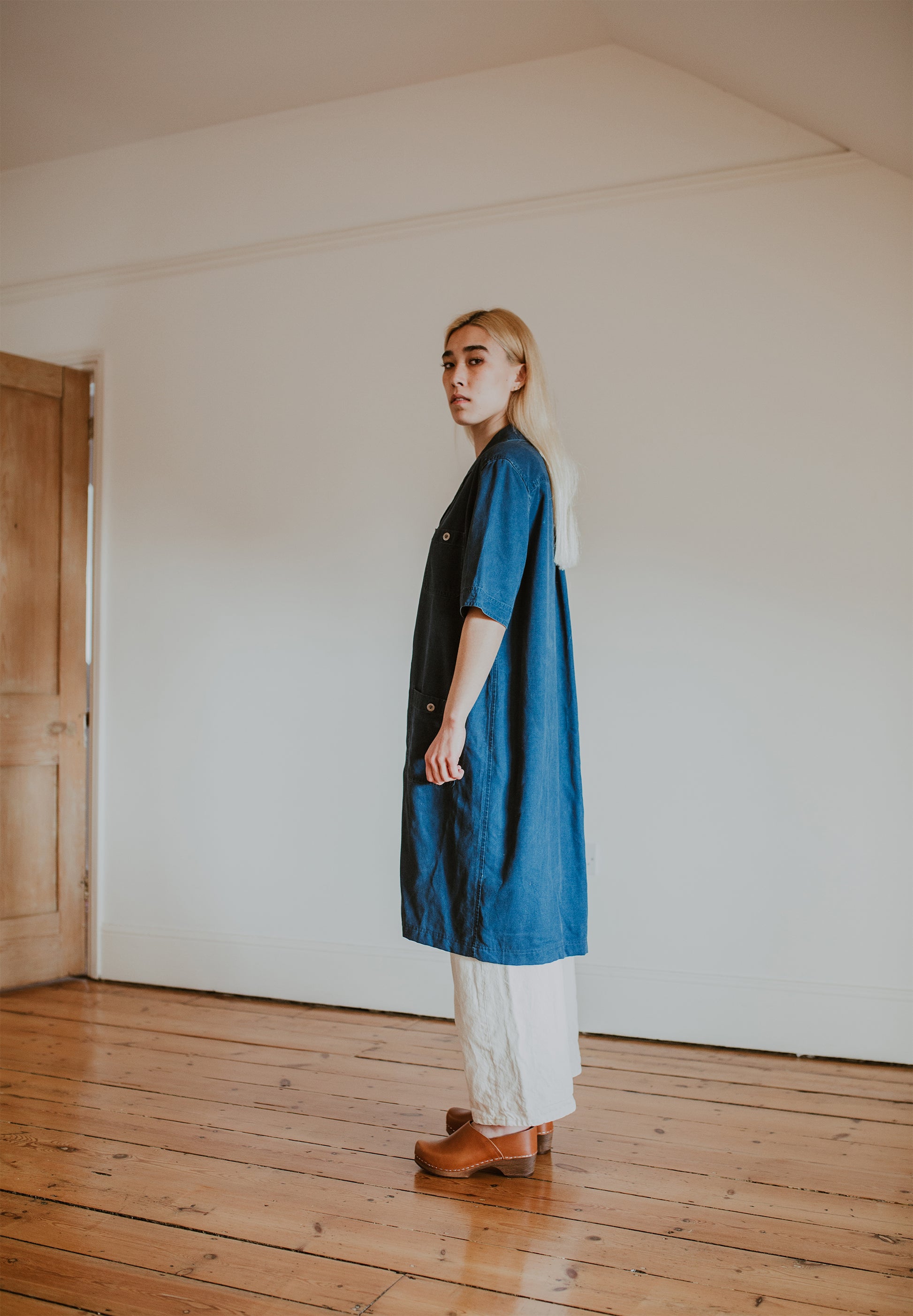 woman wears denim shirt dress with cream jeans and  cumin tan low heel clog shoes