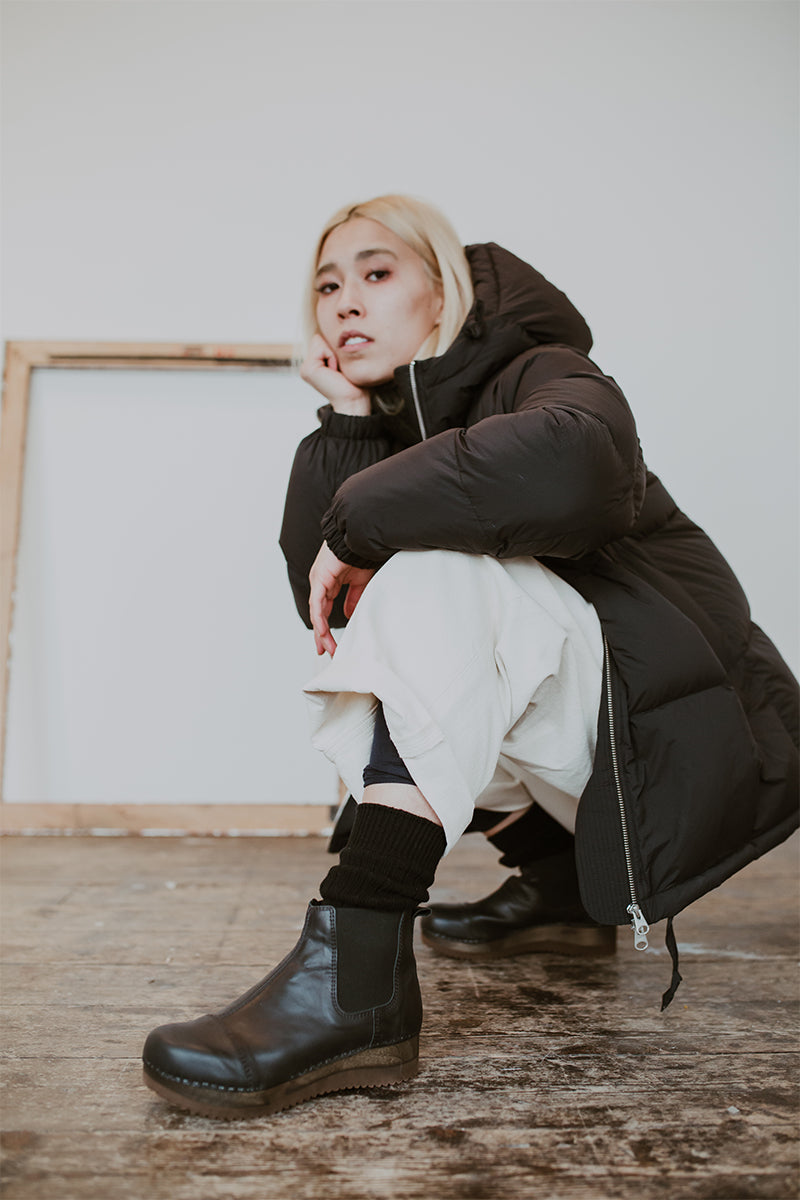 Girl wears Puffa coat and wide jeans with Black leather chelsea clog boot with flex sole